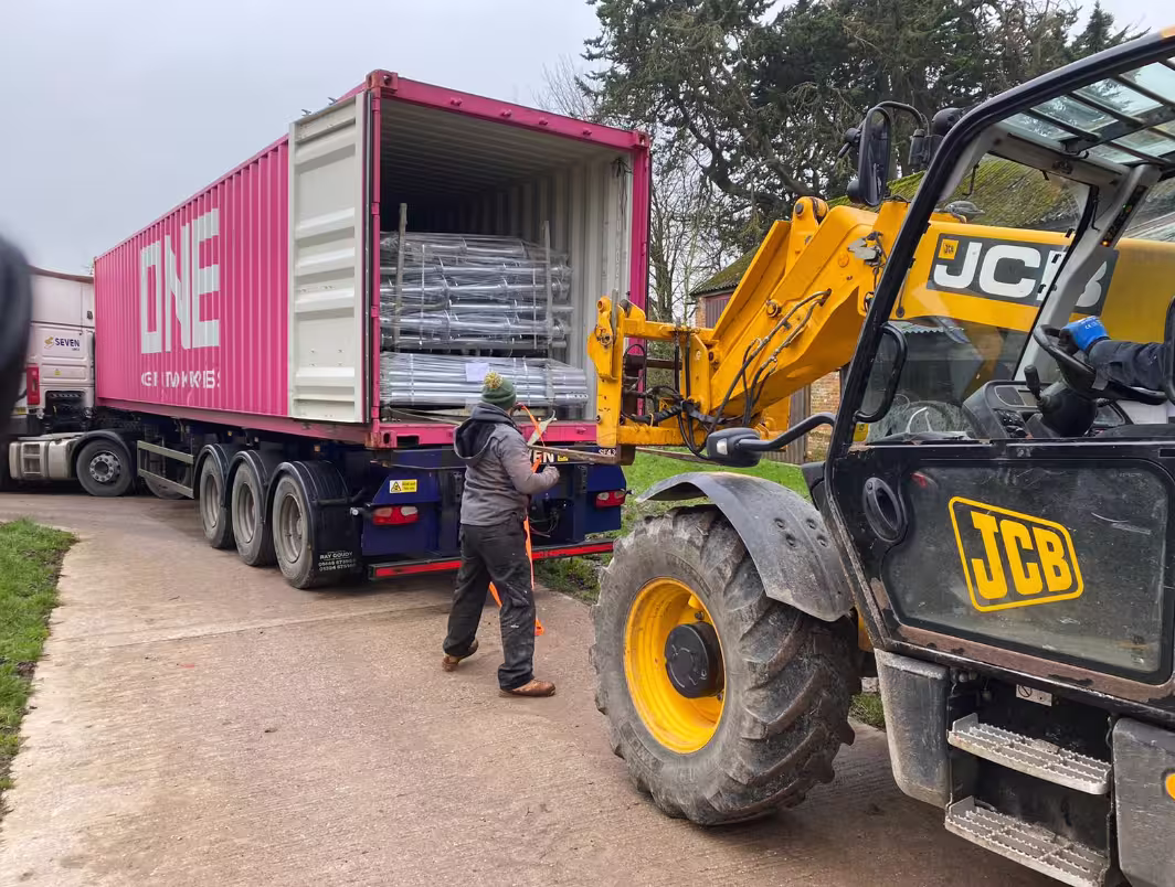JCB telehandler unloading screw piles from a delivery container